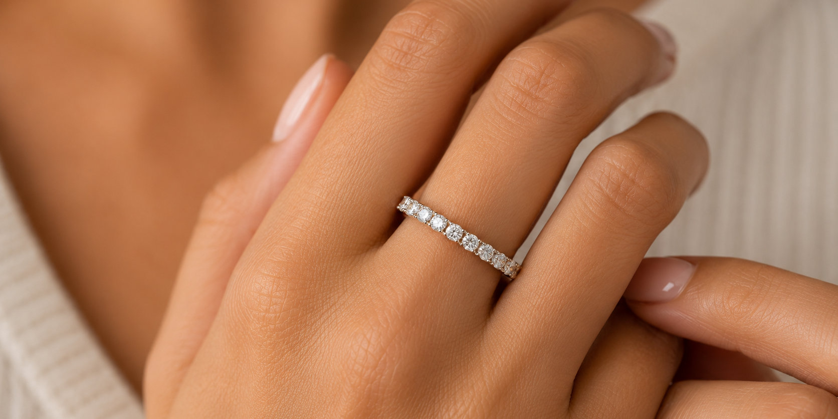 Close up image of a woman's hand with a diamond eternity band on it. 