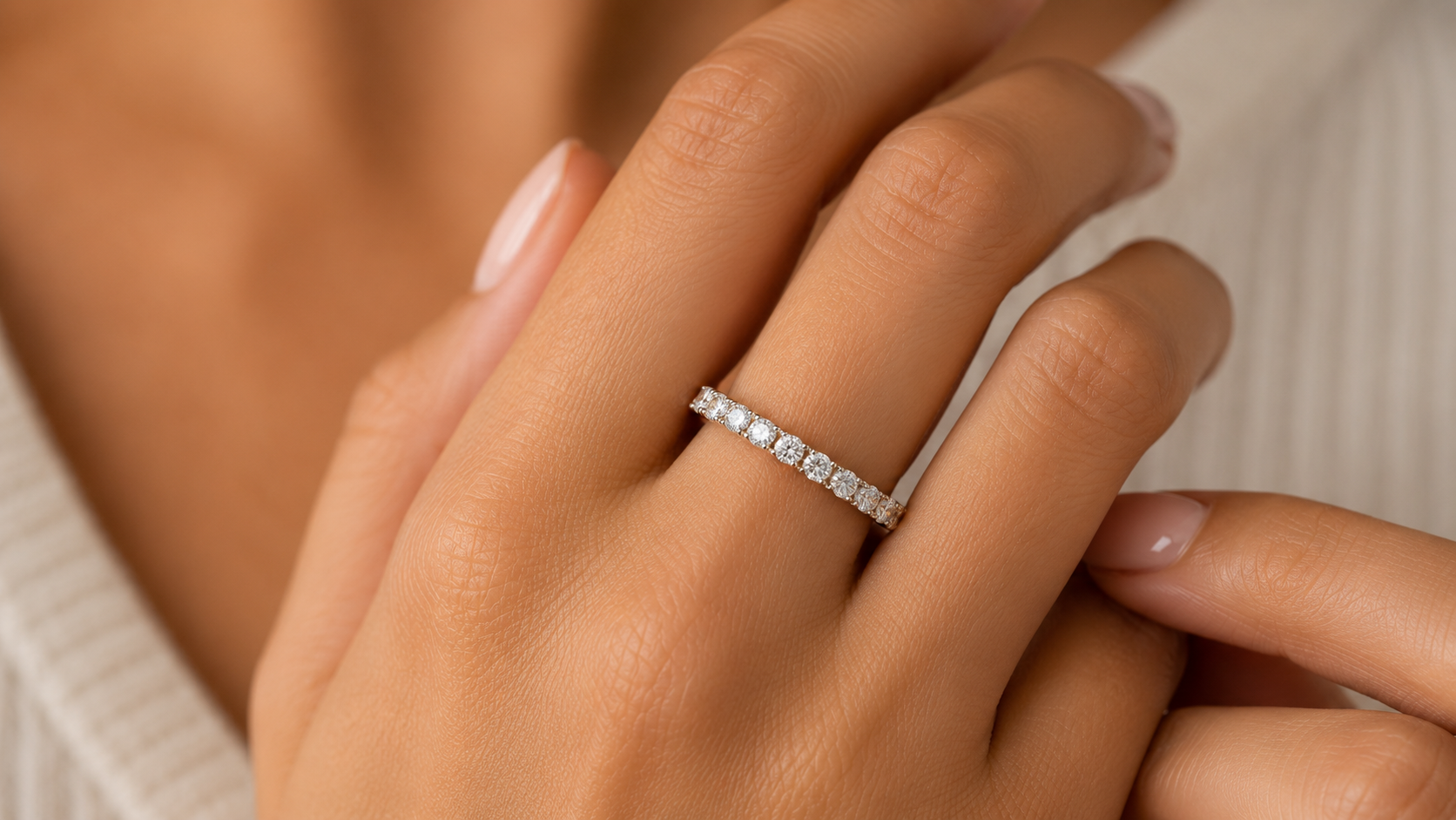 Close up image of a woman's hand with a diamond eternity band on it. 