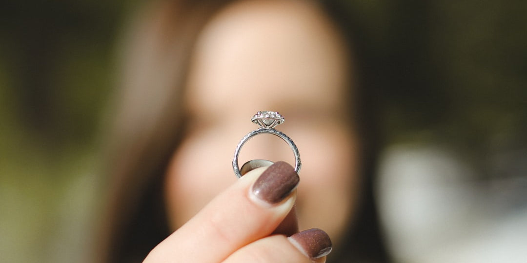 a hand holding a diamond white gold solitaire ring
