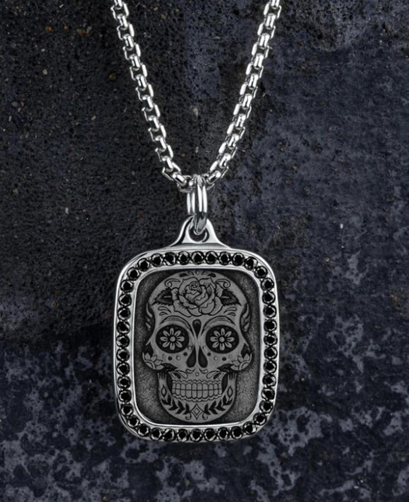 A silver necklace with a sugar skull on it.