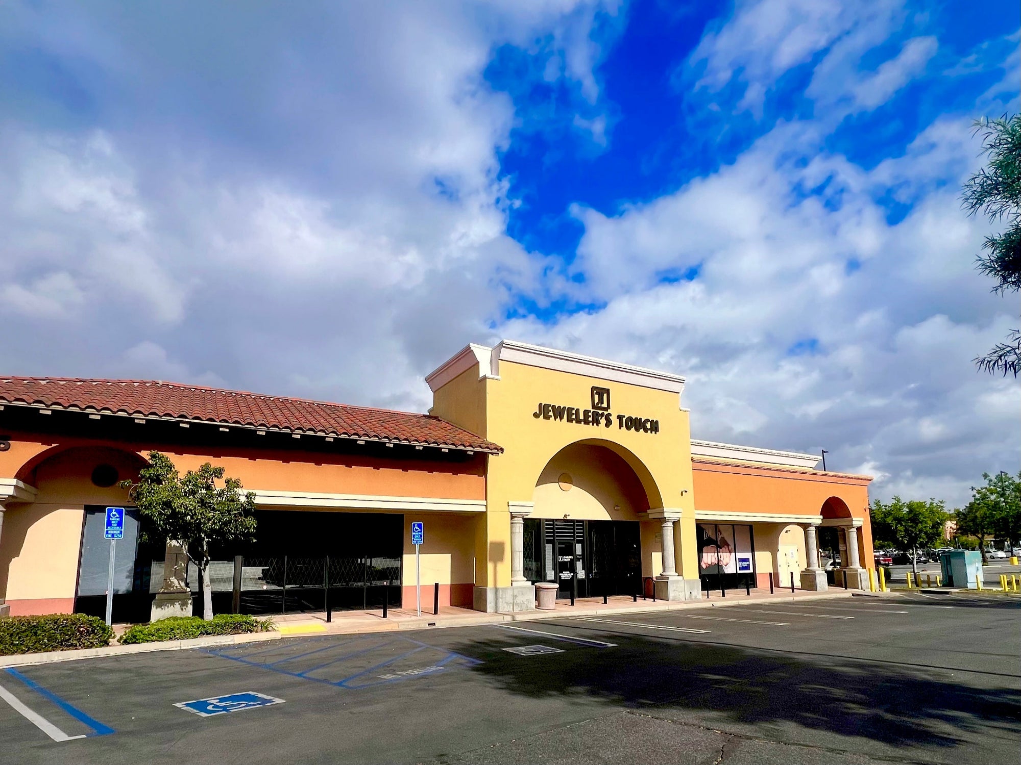 Building with 'Jeweler's Touch' sign under a blue sky with clouds