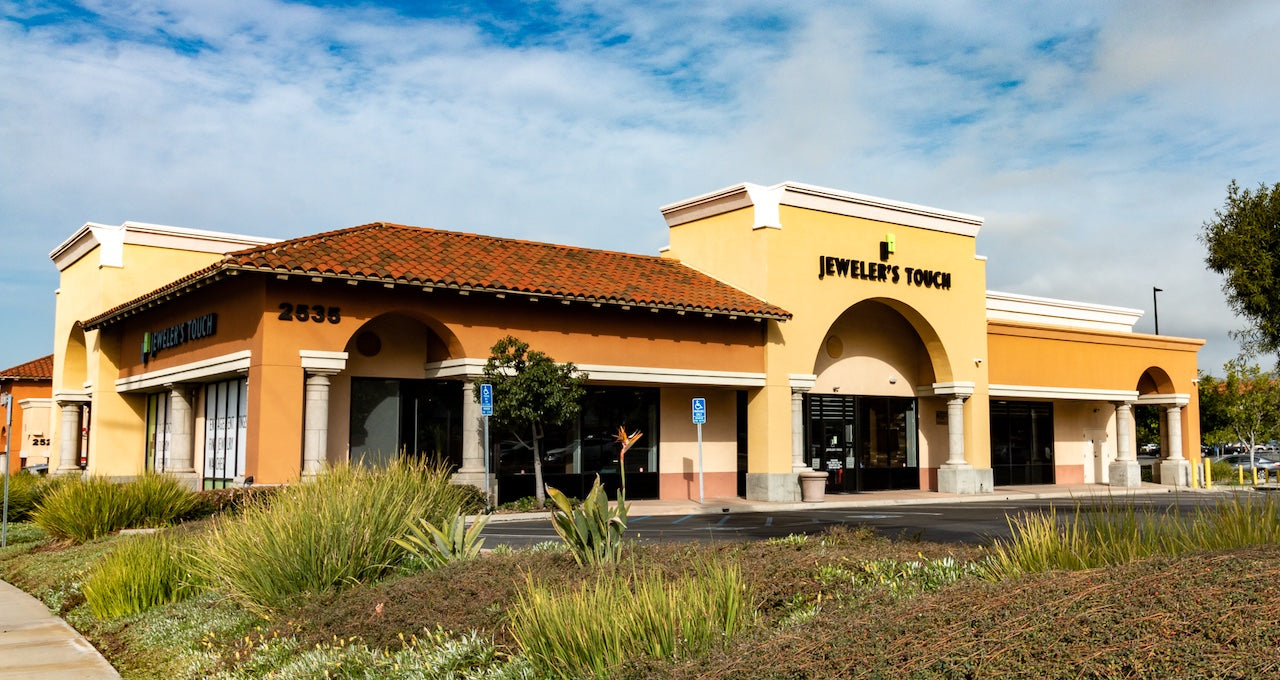 The front of a store with bushes in front of it.